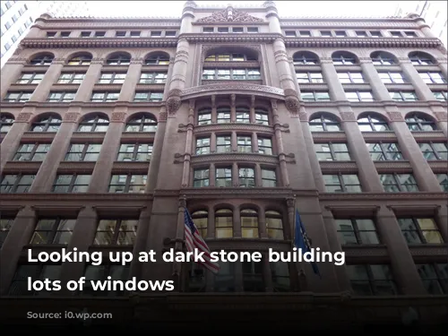 Looking up at dark stone building with lots of windows