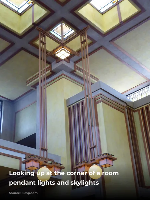 Looking up at the corner of a room with pendant lights and skylights