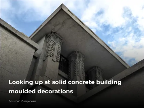 Looking up at solid concrete building with moulded decorations