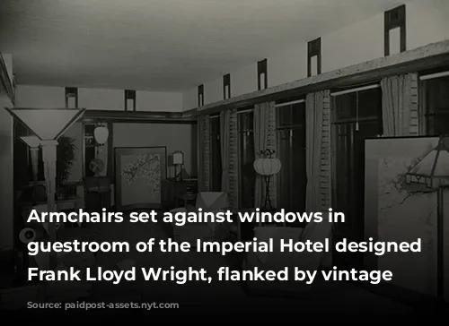 Armchairs set against windows in a guestroom of the Imperial Hotel designed by Frank Lloyd Wright, flanked by vintage lamps. 
