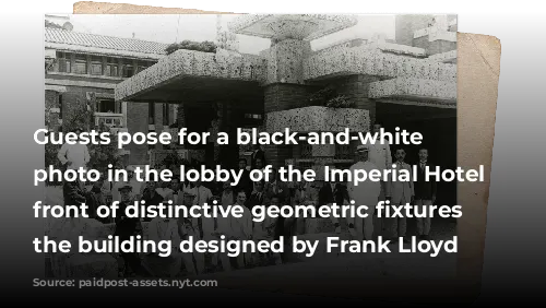 Guests pose for a black-and-white group photo in the lobby of the Imperial Hotel in front of distinctive geometric fixtures of the building designed by Frank Lloyd Wright. 
