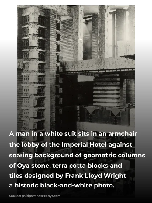 A man in a white suit sits in an armchair in the lobby of the Imperial Hotel against a soaring background of geometric columns made of Oya stone, terra cotta blocks and hand-textured tiles designed by Frank Lloyd Wright in a historic black-and-white photo.
