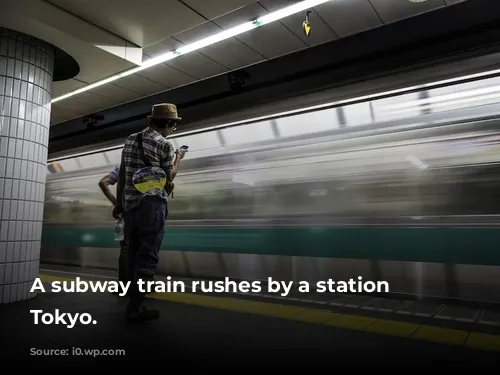 A subway train rushes by a station in Tokyo.