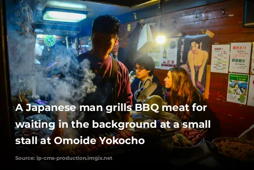 A Japanese man grills BBQ meat for customers waiting in the background at a small food stall at Omoide Yokocho