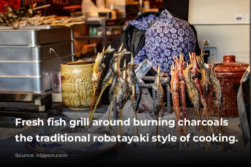 Fresh fish grill around burning charcoals in the traditional robatayaki style of cooking. (© Nippon.com)