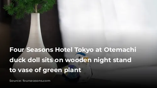 Four Seasons Hotel Tokyo at Otemachi colourful duck doll sits on wooden night stand next to vase of green plant