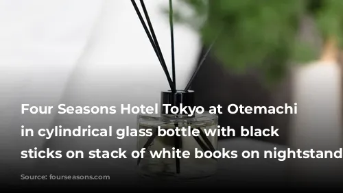 Four Seasons Hotel Tokyo at Otemachi diffuser in cylindrical glass bottle with black reed sticks on stack of white books on nightstand