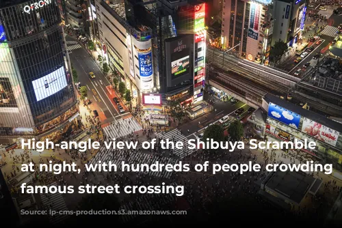 High-angle view of the Shibuya Scramble Crossing at night, with hundreds of people crowding the famous street crossing