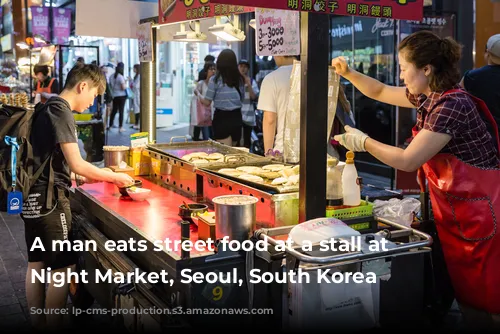 A man eats street food at a stall at Myeong-Dong Night Market, Seoul, South Korea