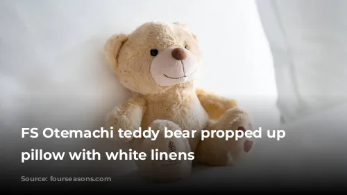 FS Otemachi teddy bear propped up on pillow with white linens