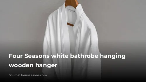 Four Seasons white bathrobe hanging on wooden hanger