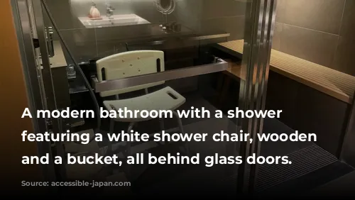 A modern bathroom with a shower area featuring a white shower chair, wooden bench, and a bucket, all behind glass doors.