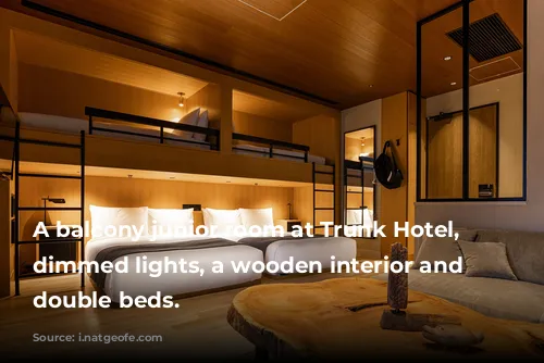 A balcony junior room at Trunk Hotel, with dimmed lights, a wooden interior and large double beds.