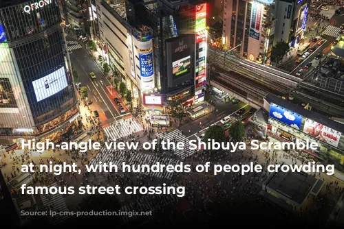 High-angle view of the Shibuya Scramble Crossing at night, with hundreds of people crowding the famous street crossing